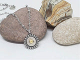 Close up of round stainless steel beaded bezel nickel bullet pendant displayed on a rock with stainless beaded chain.