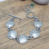 Genuine buffalo nickel coin link bracelet on wood background.