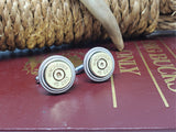 Cuff links with Winchester 45 Colt bullet casings in brass, displayed on a burguny book with rope and antler in background.