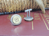 Cuff links with Winchester 45 Colt bullet casings in brass, displayed on a burguny book with rope and antler in background.  One cuff link is facing forward, the other is sitting on head to show the cufflink base.