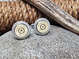 Pair of brass Winchester 45 Colt bullet casing cuff links displayed on a stone with a rope and antler in background.