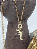 Gold pistol bullet necklace displayed on dark hand form with brass .22 Hornet casing ring and delicate gold stainless chain