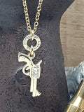 Close up of gold pavé pistol charm necklace with repurposed .22 Hornet brass casing connector