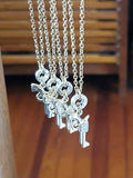 Group of gold pistol bullet necklaces hanging together, showing petite pavé pistol charms on delicate chains