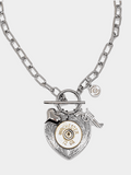 Photo of a 12 gauge shotshell mounted on a heart shaped pendant flanked with a puffy heart charm and pistol charm flat layed on a white background.