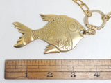 Solid brass fish pendant shown beside ruler to display size, with gold chunky paperclip chain and vintage upcycled ring fastener.