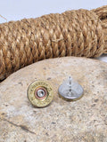 Pair of vintage Remington-Peters brand brass 28 gauge shotshell stud earrings displayed on a neutral color stone with a coil of rope in the background.  One of the earrings is turned upside down to show the stainless steel back and the earring keeper.